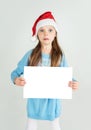 ÃÂ¡ute girl in Santa Claus hat with a white blank paper sheet wit